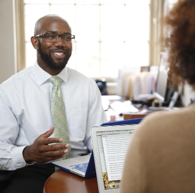 A man sitting at a desk talking to a woman.