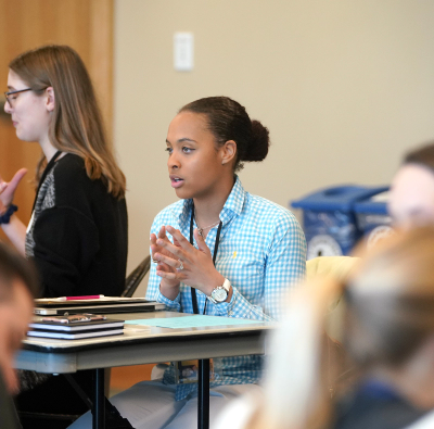 A group of people sitting at a table in a classroom.