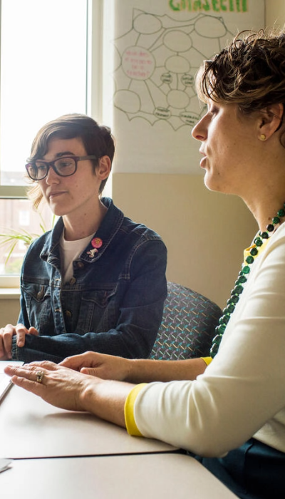 Two women sitting at a table talking to each other.