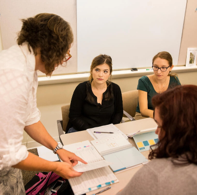 A group of people sitting around a table in a classroom.