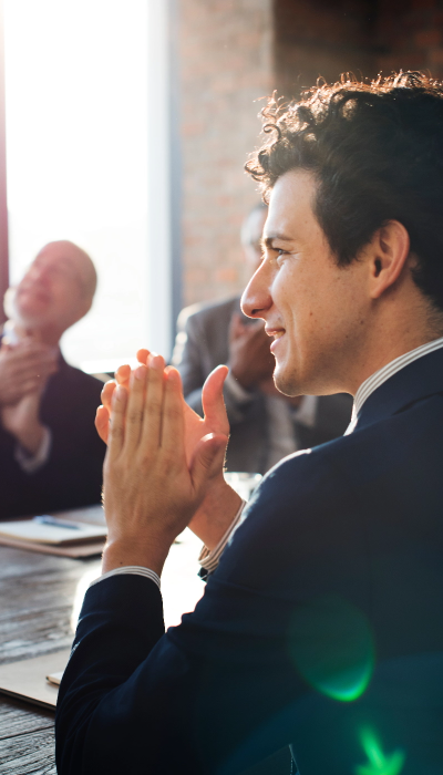 A group of business people clapping at a meeting.