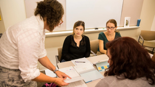 A group of people sitting around a table in a classroom.