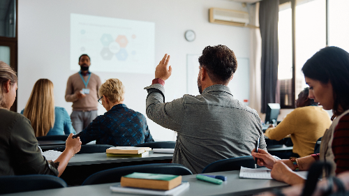A student in a lecture raising their hand.