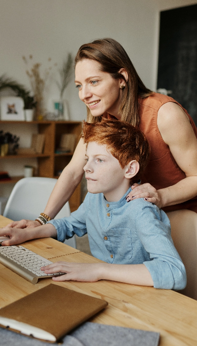 A woman and a boy working on a computer.