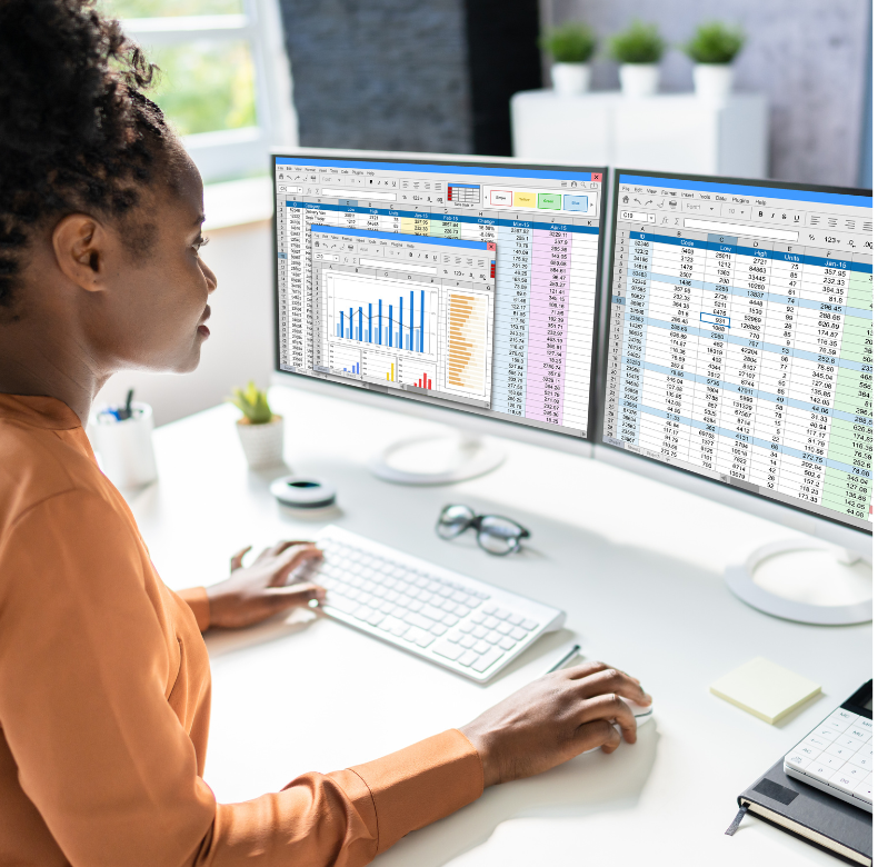 A woman sitting at a desk with two monitors in front of her.