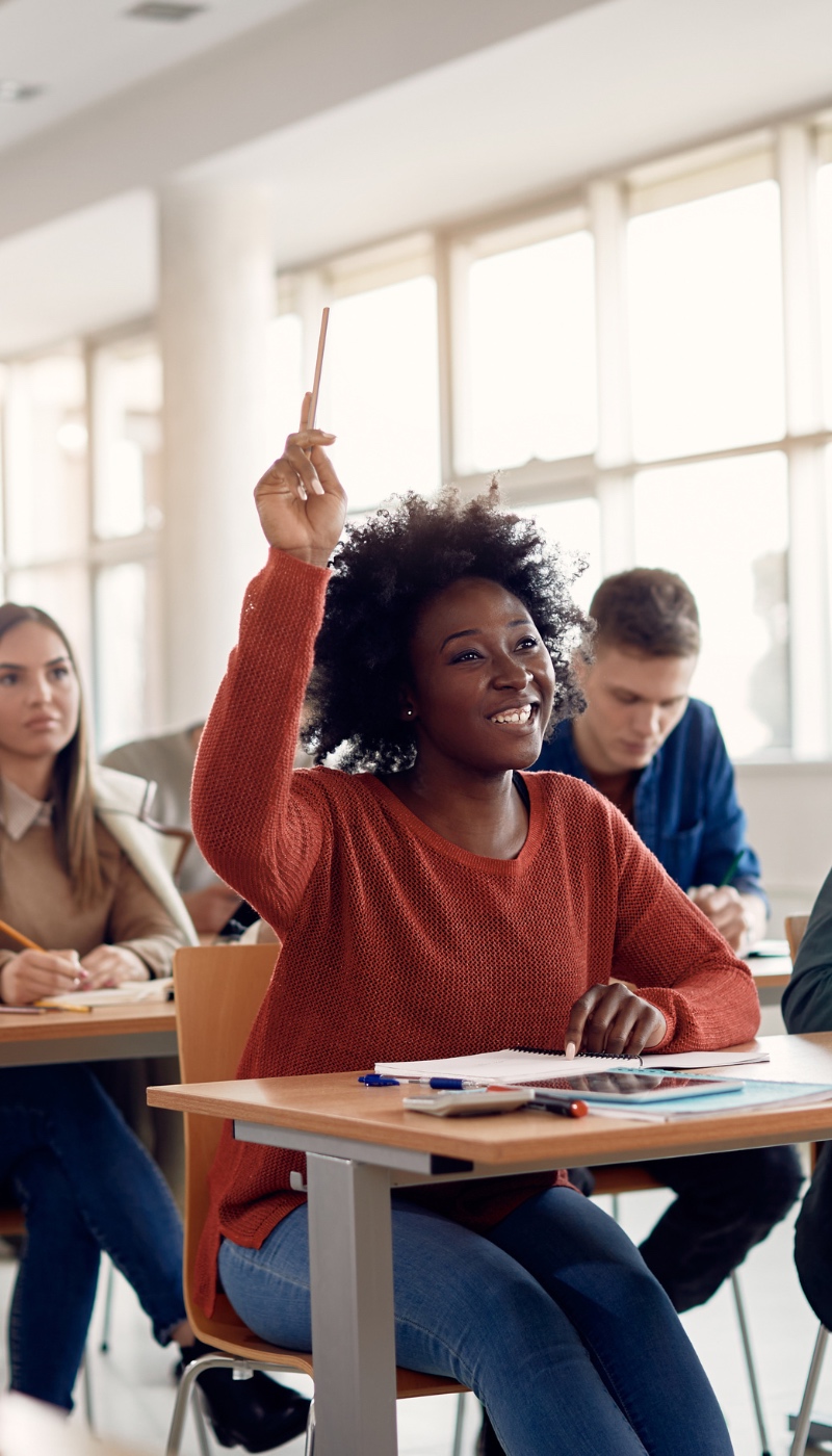 A group of students in a classroom raising their hands.