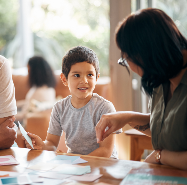 A young boy is sitting at a table with his parents.