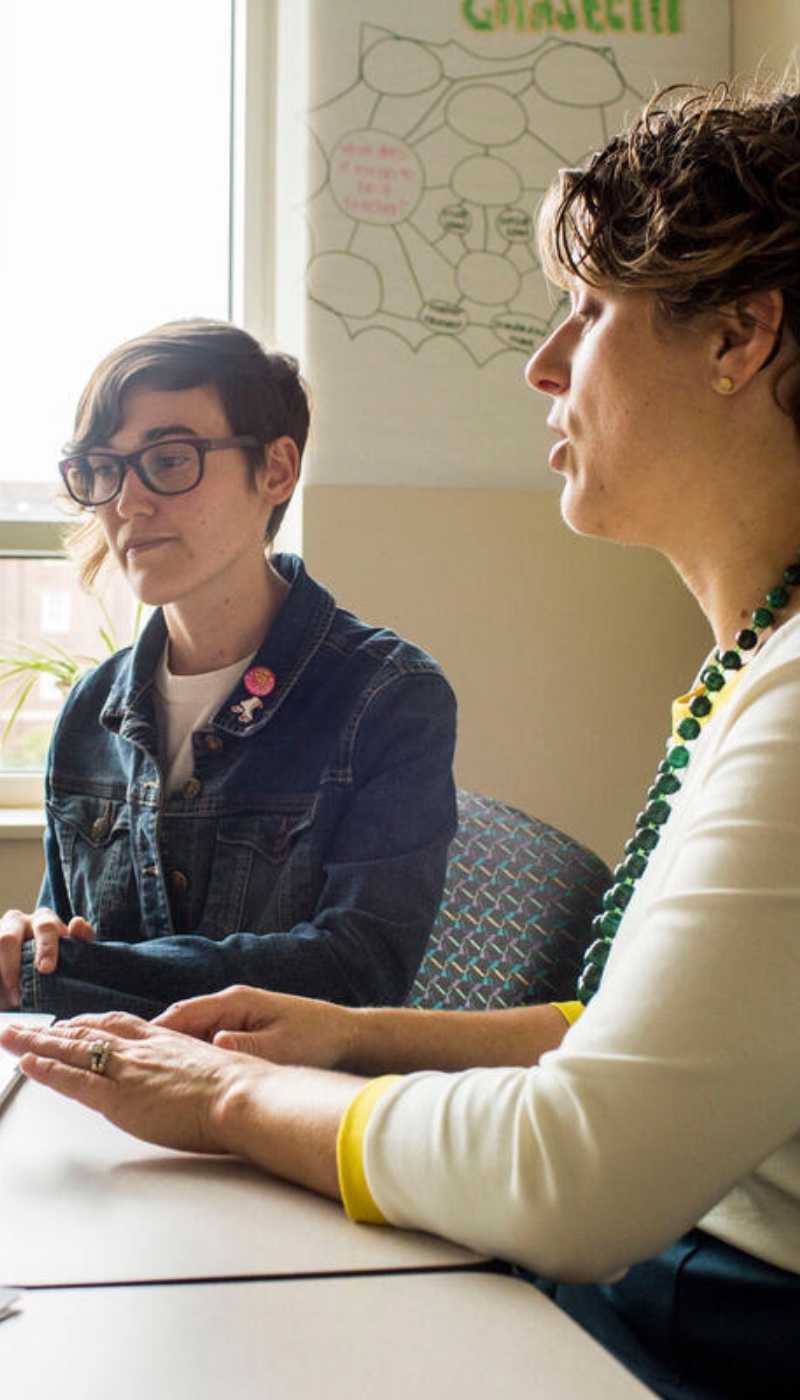 Two women sitting at a table talking to each other.