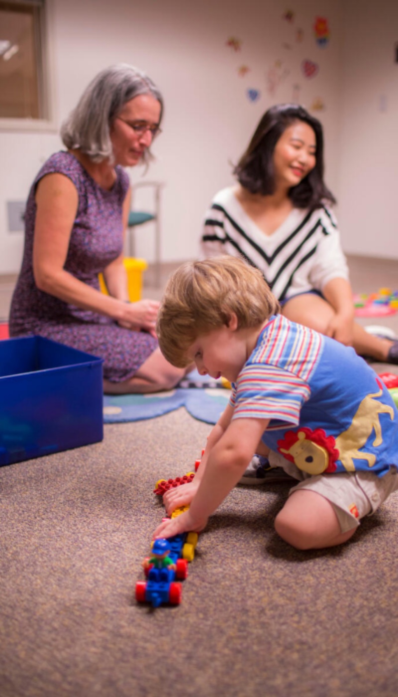 A child plays with a group of people in a room.