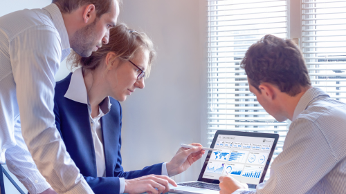 Three business people looking at a graph on a laptop.