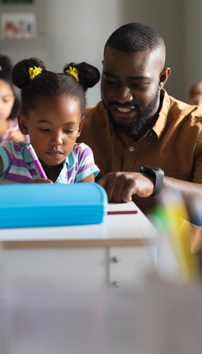 A teacher helping his student at their desk